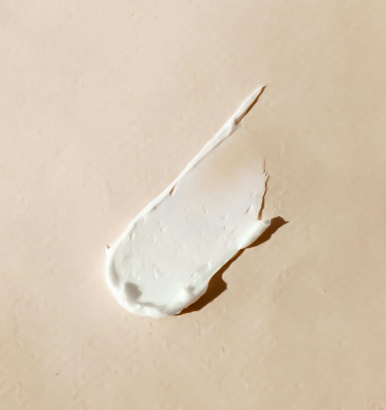Weiße Pflegecreme auf beigefarbenem Hintergrund